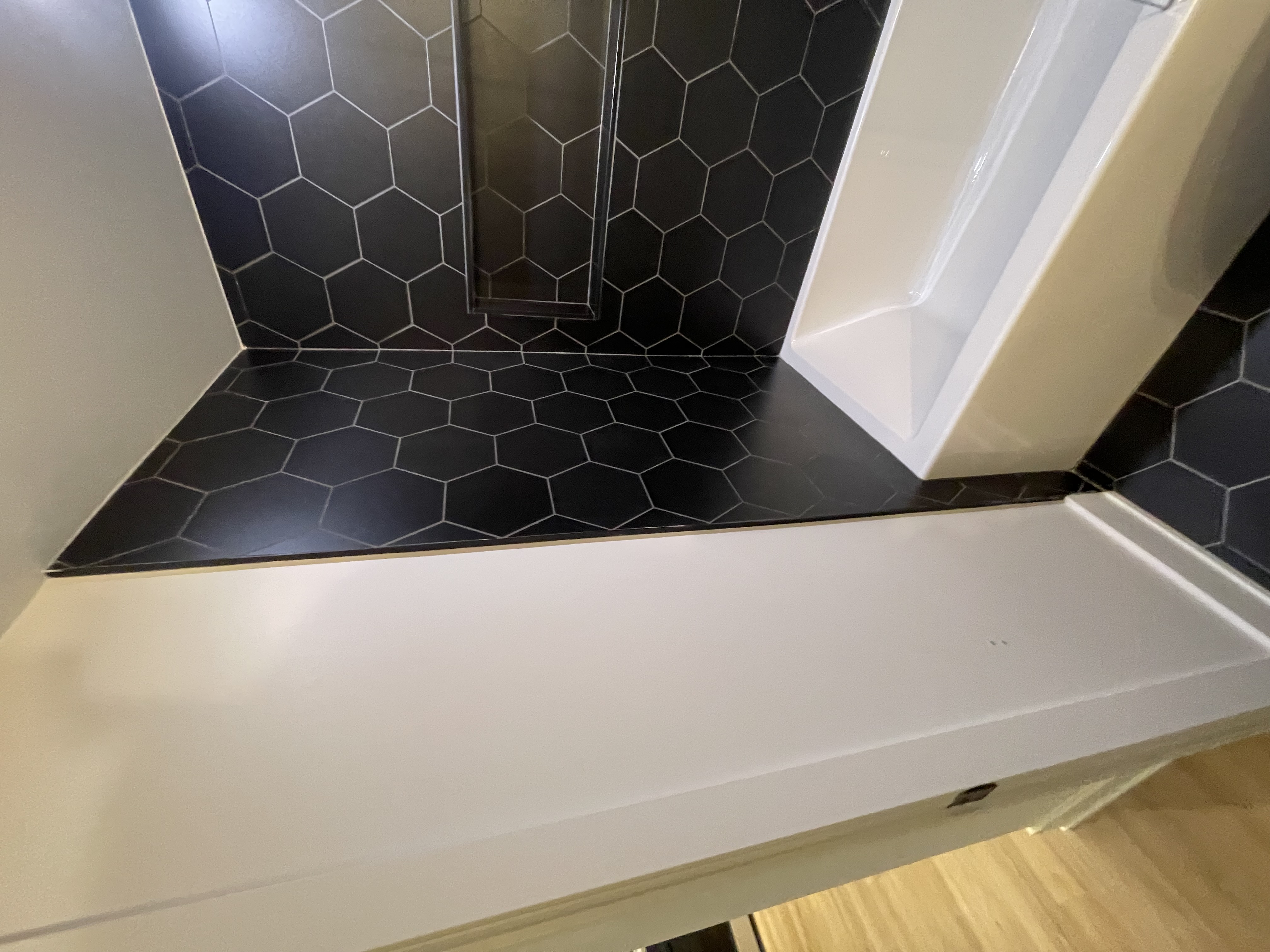 Modern black hexagon tile with clean white tub creates striking contrast — strong portfolio piece showing current design trends — Queensway, Hamilton | MTC Renovations