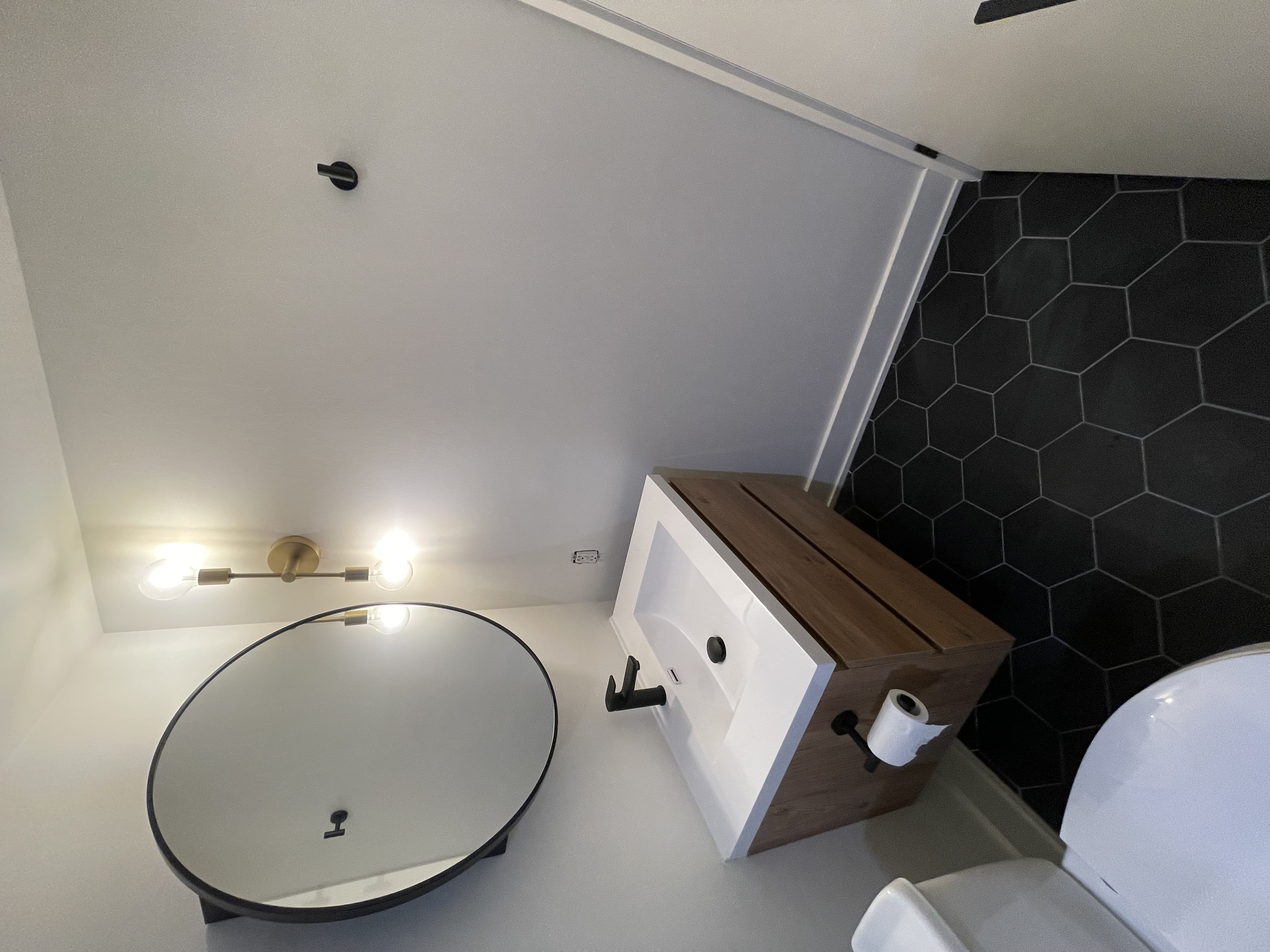 Modern powder room with striking black hex tile and warm wood vanity — strong portfolio piece with current design trends — Queensway, Hamilton | MTC Renovations