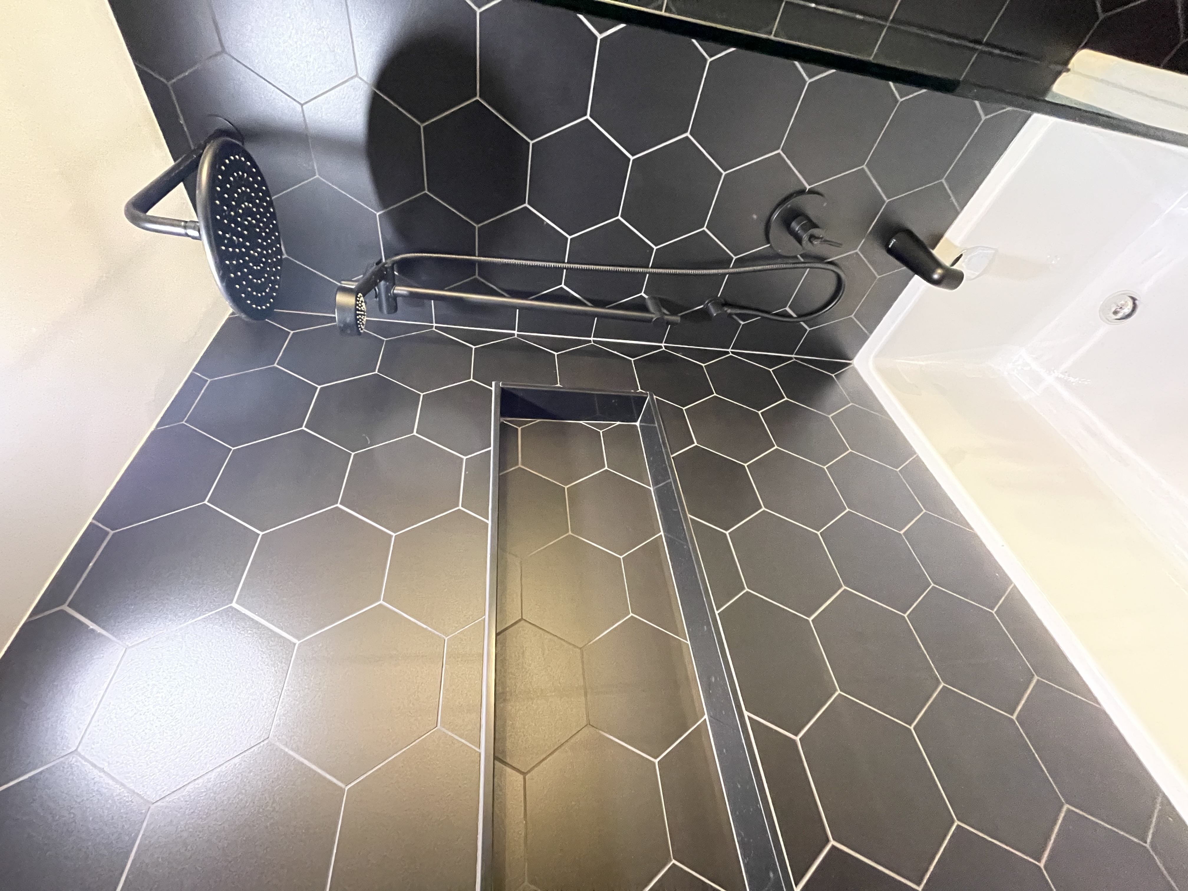 Stunning hexagon tile shower with modern black fixtures — premium portfolio shot showcasing current design trends — Queensway, Hamilton | MTC Renovations