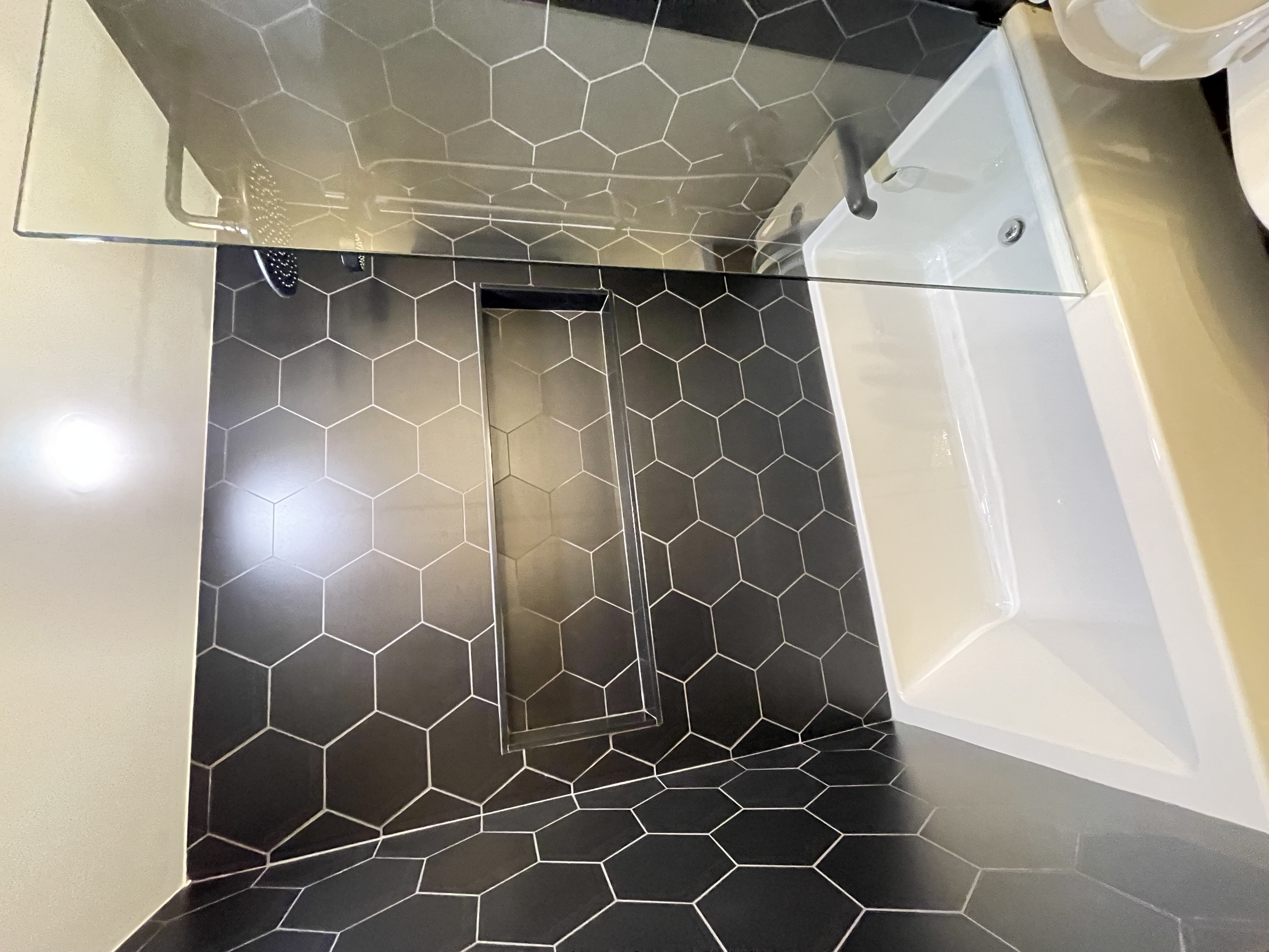 Stunning finished bathroom with dramatic black hexagon tile and clean modern fixtures — premium portfolio shot — Queensway, Hamilton | MTC Renovations