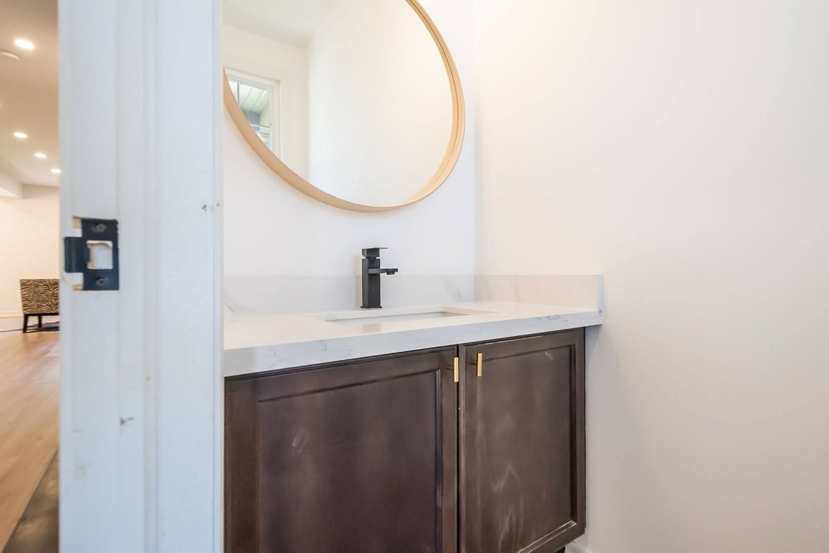 Clean modern powder room with warm wood vanity and brass accents — premium portfolio shot with strong material contrast — Stonehenge, Hamilton | MTC Renovations
