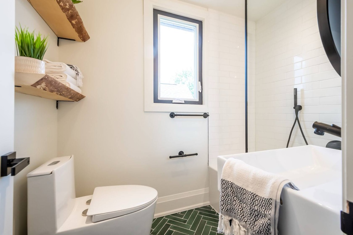 Bright modern bathroom with striking green herringbone floor and live-edge wood shelving — premium portfolio shot — Rosedene, Hamilton | MTC Renovations