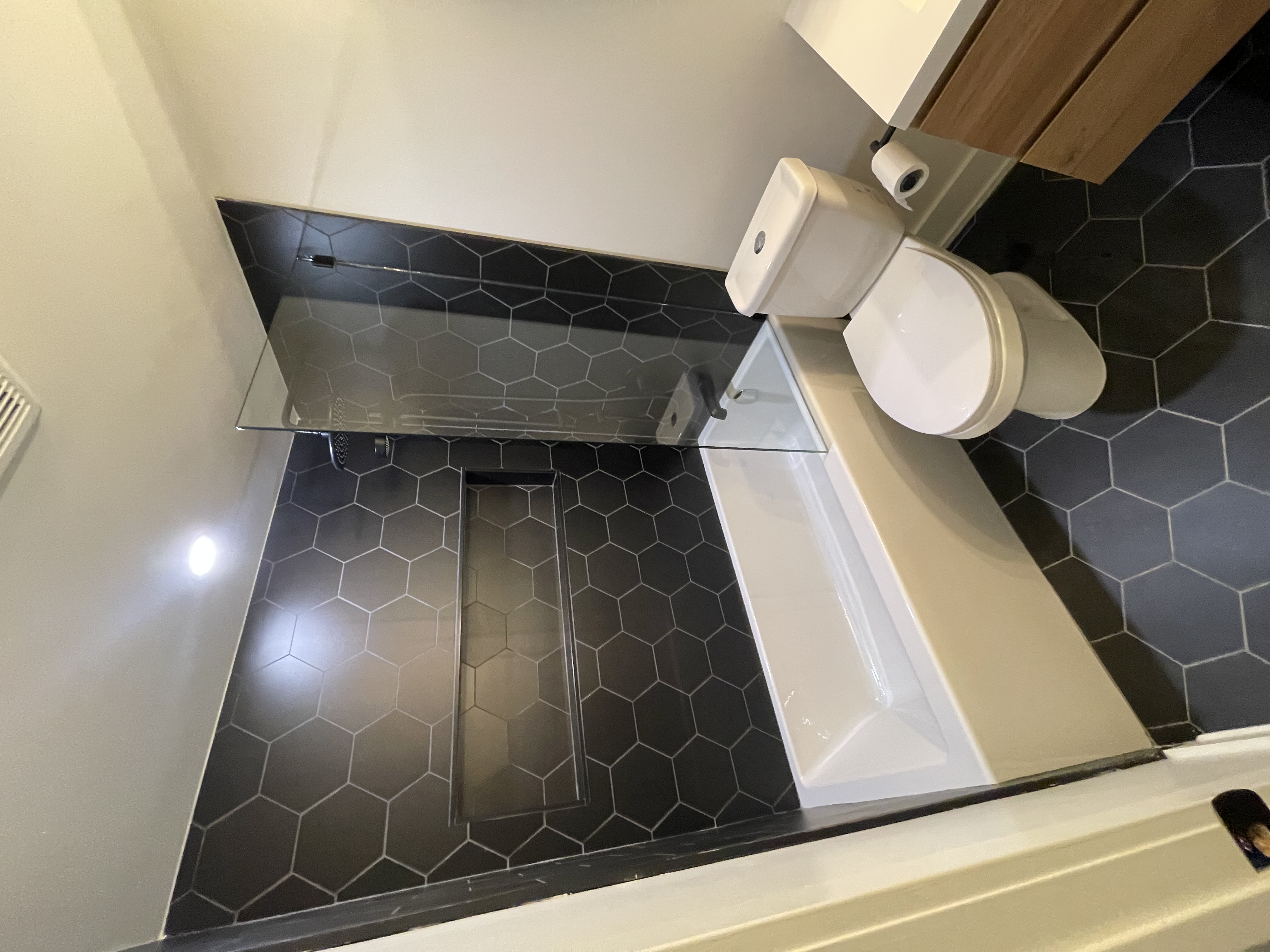 Modern bathroom with striking black hexagon tile feature wall and coordinated floor — Queensway, Hamilton | MTC Renovations