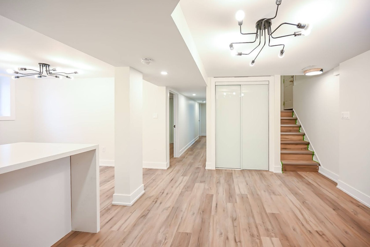 Bright finished basement with modern fixtures and warm wood flooring — Winchester, Hamilton | MTC Renovations