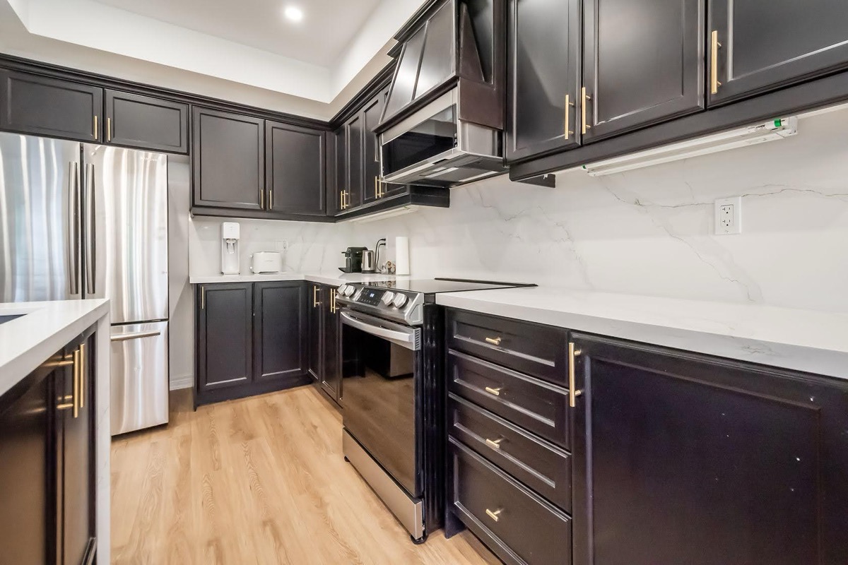 Premium finished kitchen with dramatic dark cabinets, quartz counters, and professional wide-angle composition — Stonehenge, Hamilton | MTC Renovations