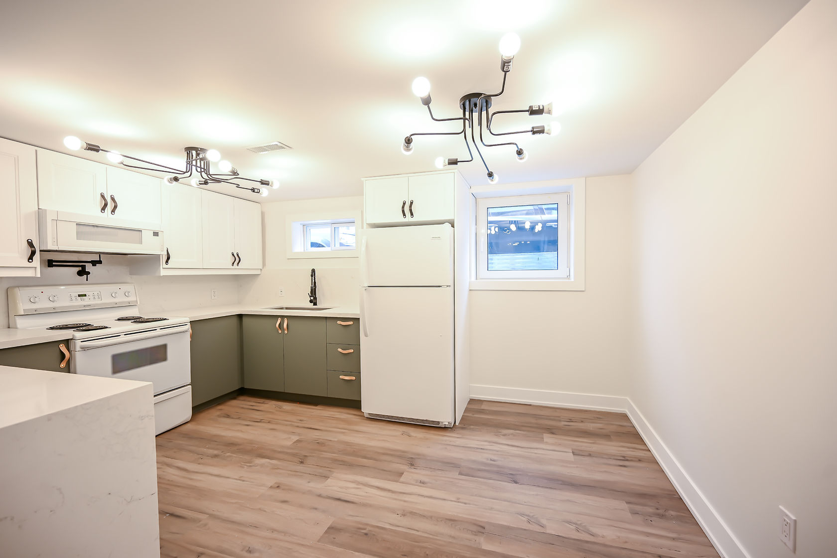 Clean finished kitchen with two-tone cabinets and modern fixtures — strong portfolio shot despite artificial lighting — Winchester, Hamilton | MTC Renovations