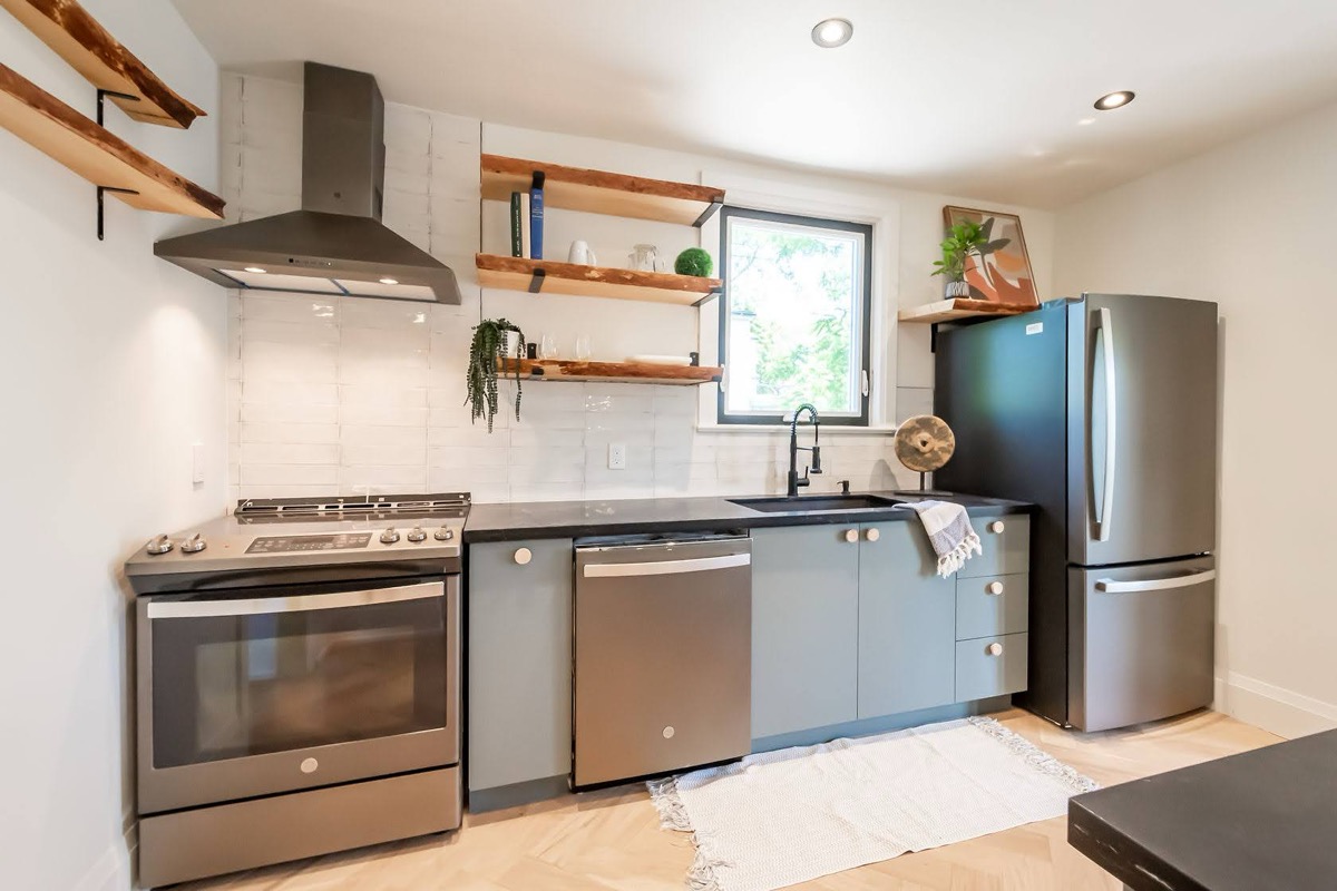 Professional wide-angle finished kitchen with warm wood shelving, modern blue cabinets, and excellent natural lighting — premium portfolio shot — Rosedene, Hamilton | MTC Renovations