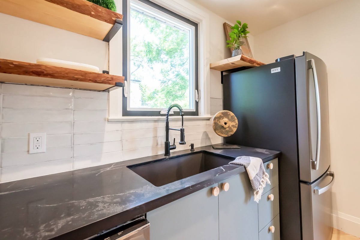 Bright finished kitchen with striking dark countertops and warm wood shelving — strong portfolio piece with good material contrast — Rosedene, Hamilton | MTC Renovations
